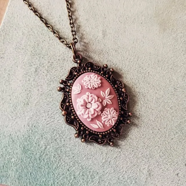 Pink polymer clay cameo with white flowers in a copper frame
