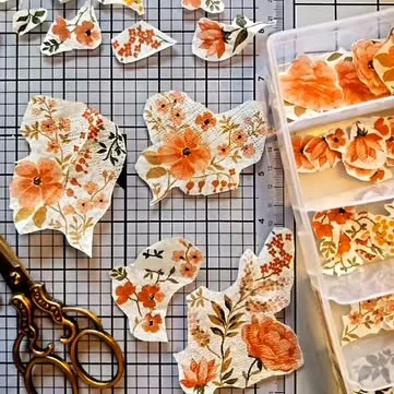 Hand-cut floral paper pieces on a cutting mat